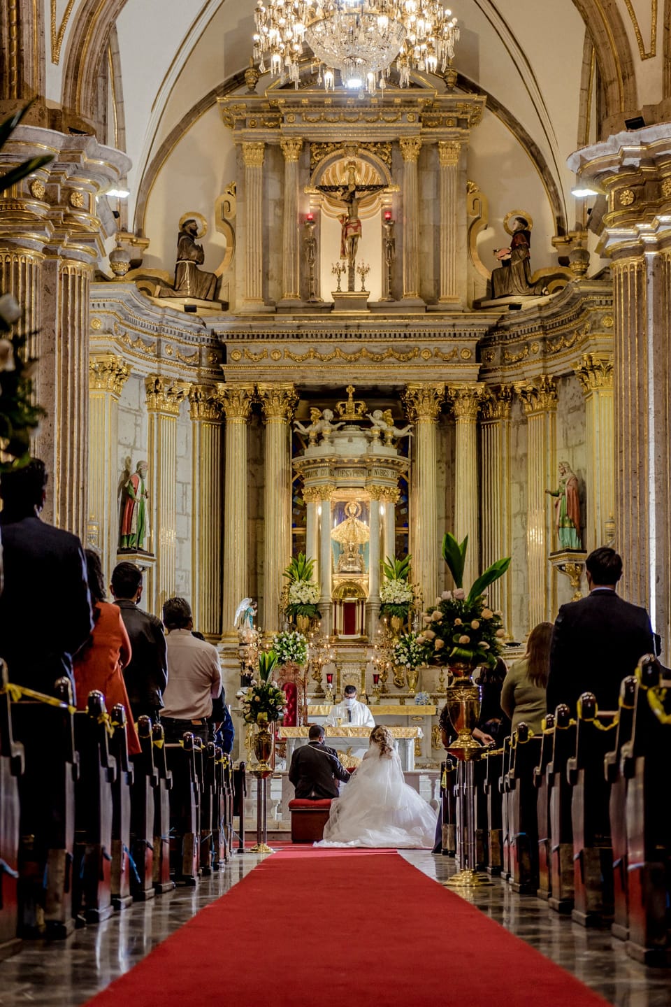 Brautpaar kniet bei der kirchlichen Trauung vor dem goldenen Barockaltar
