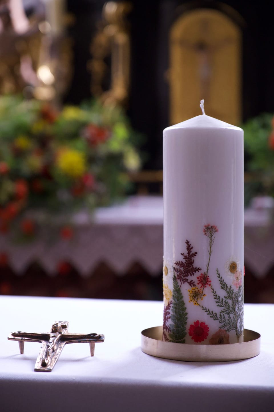 Weiße Taufkerze mit Blumenschmuck in einer hellen Kirche